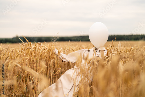 Beige trench coat laying around wheat field with white balloon inside photo