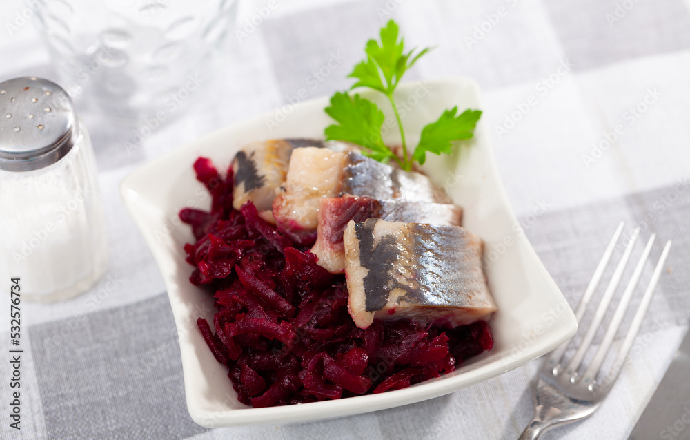 Sliced herring with beetroot served table. Chopped fish with grated beet on table.