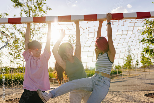 Chinese friends having fun hanging from the crossbar of a goal