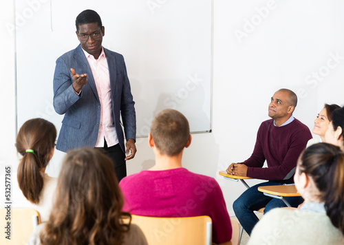 Happy middle aged coach businessman giving talk at modern office conference to multiethnic team