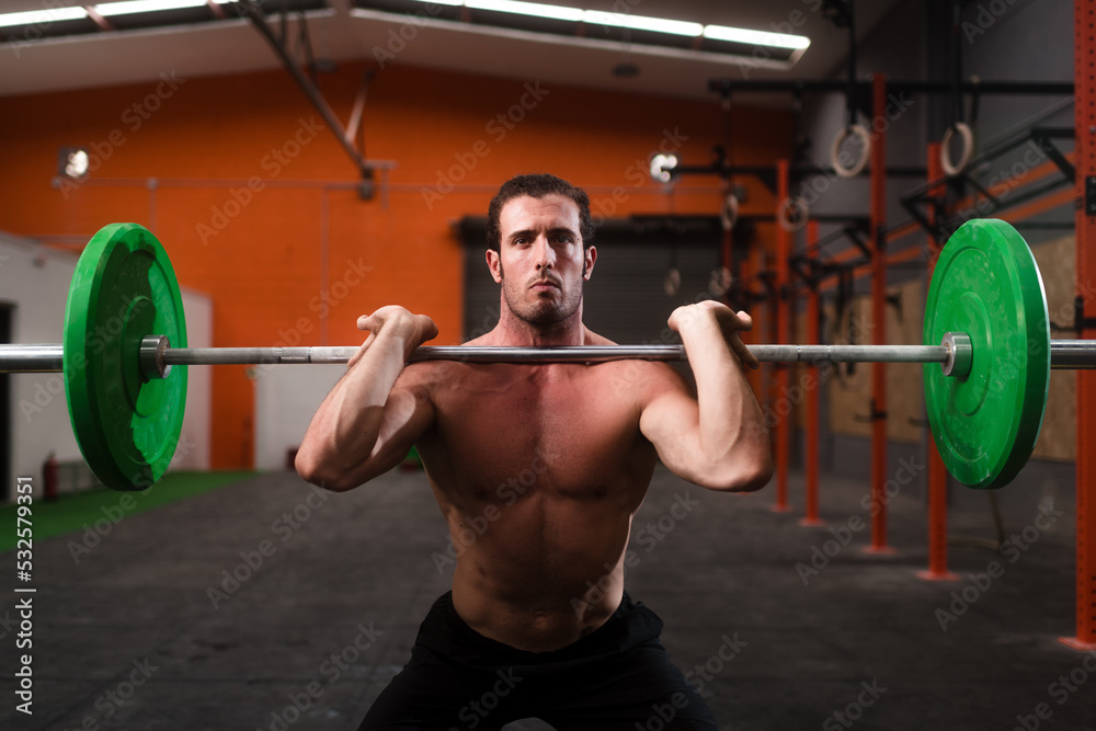 Shirtless athlete performing barbell jerk squad
