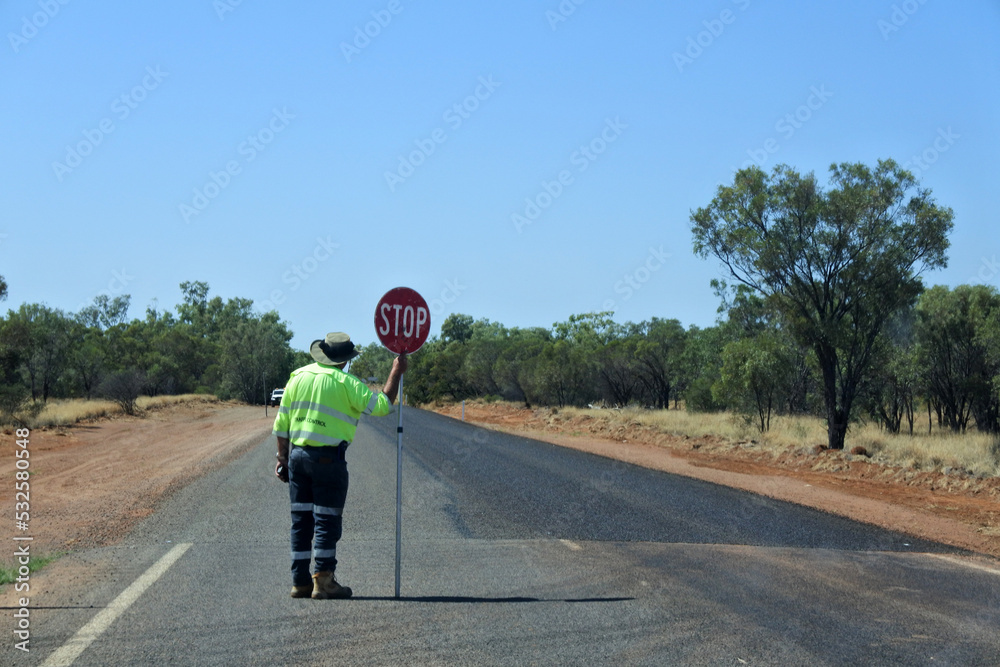 Australian road worker holding a stop sign on an outback road