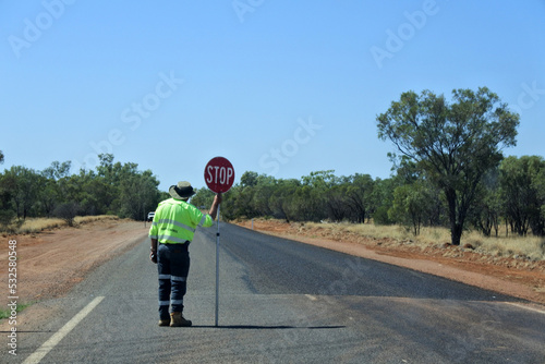 Australian road worker holding a stop sign on an outback road