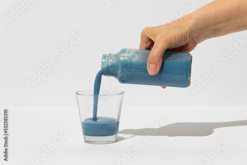 Woman pouring blue spirulina healthy superfood drink into glass photo