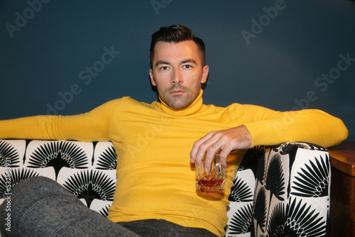 Handsome Man on Stylish Sofa With Glass of Whiskey photo