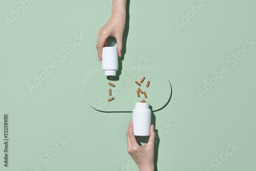 Pills spilling out of a pill bottle on green photo