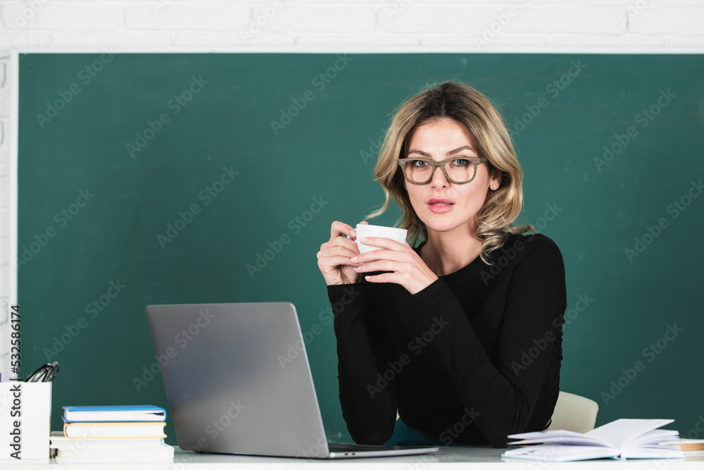 Portrait of female teacher teaching drinking coffee in classroom on blackboard. Portrait of female teacher teaching drinking coffee in classroom on blackboard.