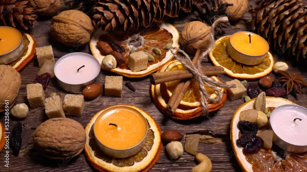 Natural composition in hygge style with candles, orange slices, fragrant spices, walnuts and pine cones on an old vintage wooden board background. Natural composition in hygge style with candles, orange slices, fragrant spices, walnuts and pine cones on an old vintage wooden board background.