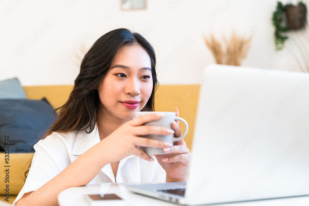 Woman drinking a cup of coffee while using laptop. Woman drinking a cup of coffee while using laptop.