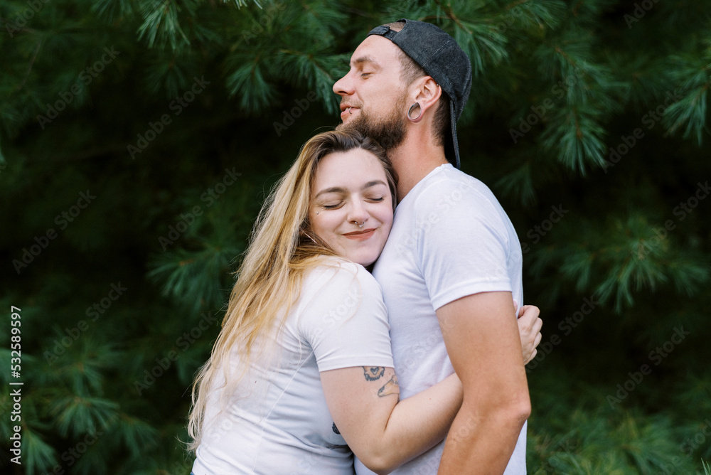 Young smiling man and woman hugging each other outdoors