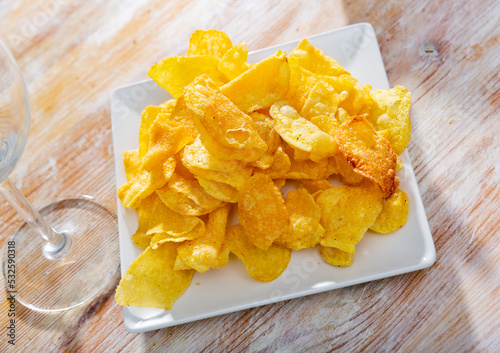 Crispy salty organic potato chips with natural taste served on plate. Popular junk food concept..