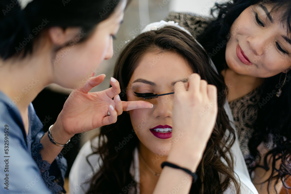 A Bridesmaid Applies Mascara on a Bride A Bridesmaid Applies Mascara on a Bride