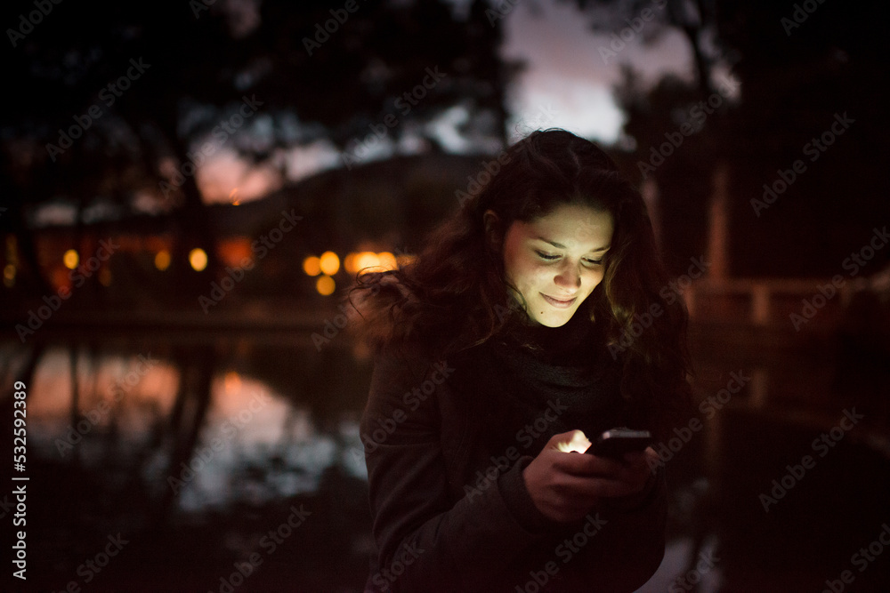 Smiling woman with cellphone illuminating her face Smiling woman with cellphone illuminating her face