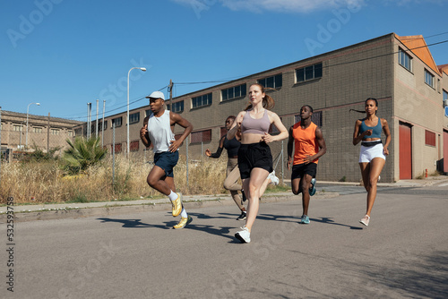 Athletes running fast on asphalt road