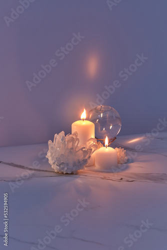 Candles burning in dark near crystals and glass ball