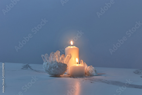 Natural quartz crystals and burning candles in dark
