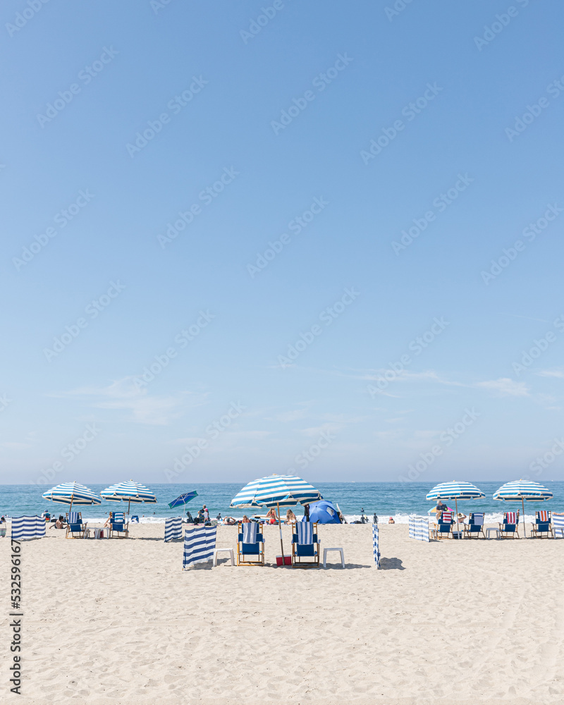 Tiny people on the beach with striped umbrellas Tiny people on the beach with striped umbrellas