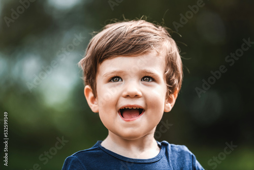 Portrait of a beautiful and happy-looking white boy, enjoying a sunny summer day in a natural park. Concept of outdoor activities for children and the joy of being in nature. Emotional kid.