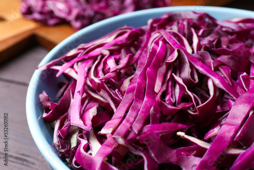 Fresh chopped red cabbage in bowl on table, closeup