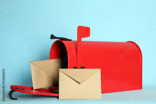 Open red letter box with envelopes on turquoise background photo