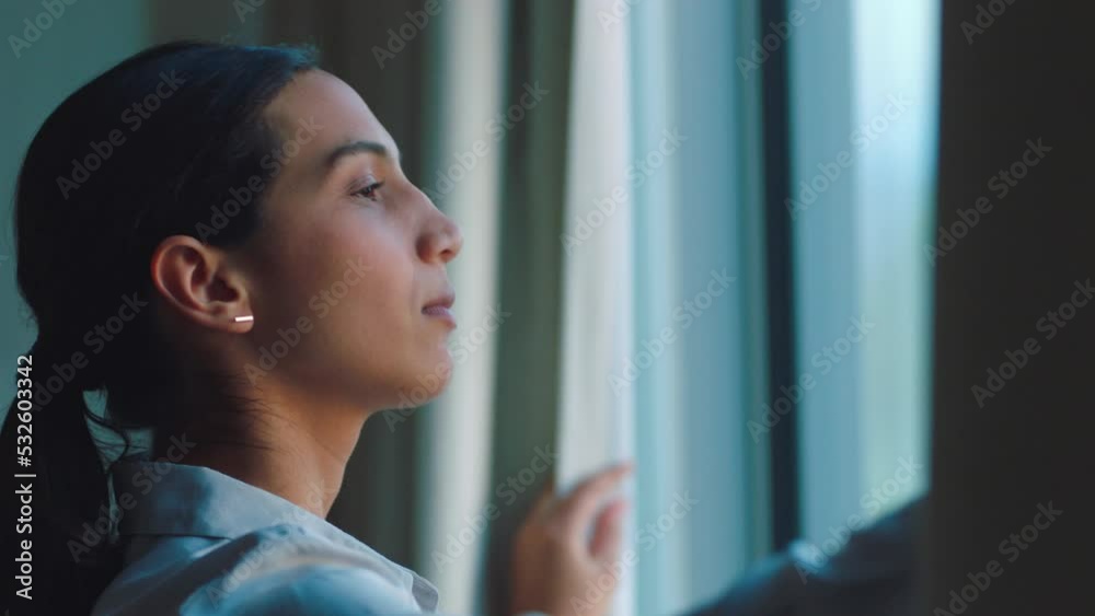 Young woman open curtain after a peaceful, relaxing sleep gets ready to go to work and lets the sun shine on her face. Happy to start her healthy morning skincare, beauty, make up and hair routine
