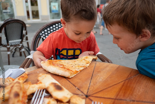 Hungry children are looking at the last pizza slice in a restaurant  photo