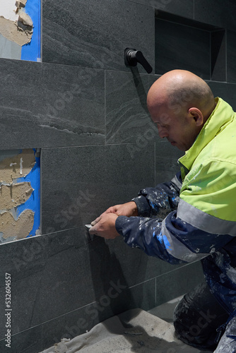 Tiler renewing grout on bathroom tiles