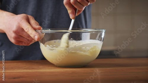 A male home chef making Bulgarian moussaka in his kitchen. Closeup shot - preparing topping with yogurt, eggs and flour.