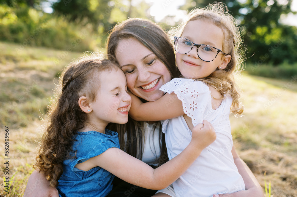 Portrait of a mother and her two daughters sitting down in a field Portrait of a mother and her two daughters sitting down in a field