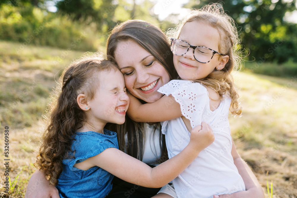Portrait of a mother and her two daughters sitting down in a field Portrait of a mother and her two daughters sitting down in a field