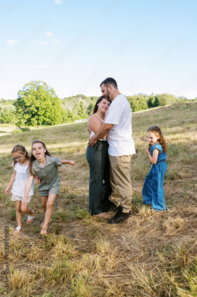 Parents hugging each other and their children running around them Parents hugging each other and their children running around them