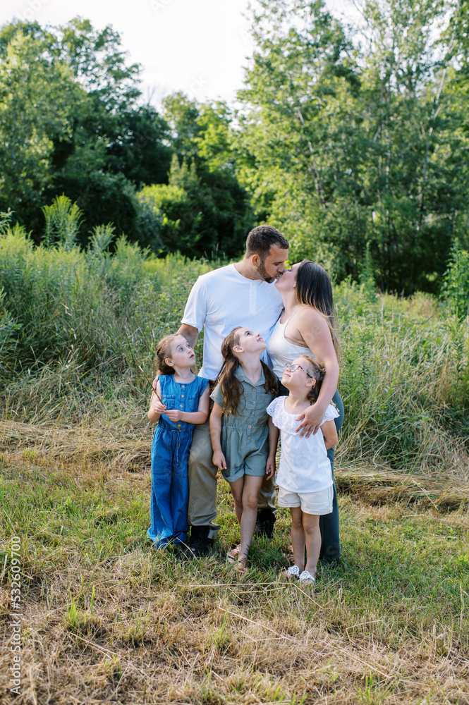 Family of five standing in a field together on a summer day Family of five standing in a field together on a summer day