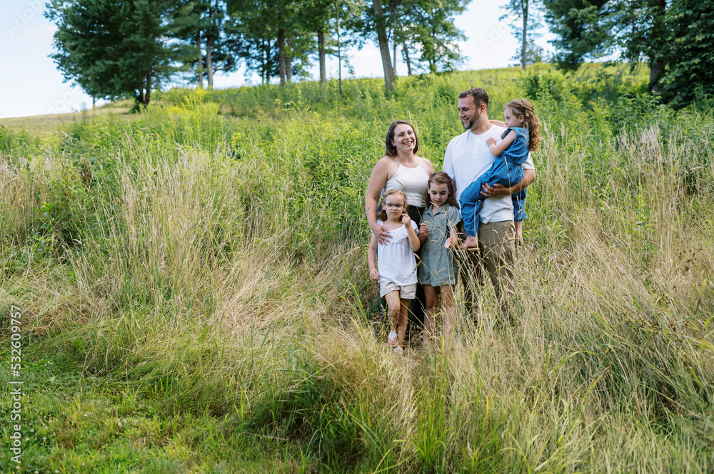 Family of five standing in a field together Family of five standing in a field together