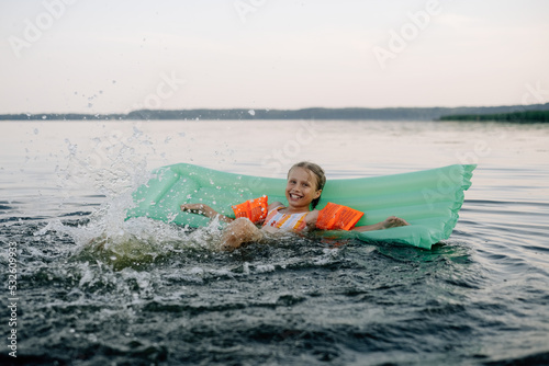 Little girl floats on an inflatable mattress