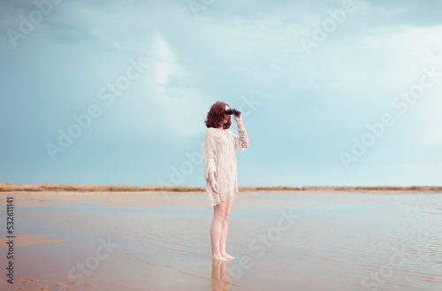 Standing woman using binoculars at wide shore
