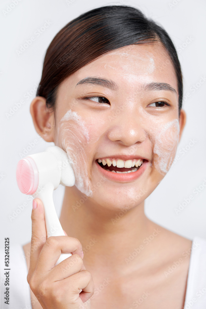 Portrait of beautiful pleased lady cleans skin with brush cleanser Portrait of beautiful pleased lady cleans skin with brush cleanser
