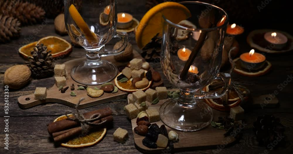 Pouring mulled wine into glasses on the background of an old vintage wooden board with cookies, chocolate, orange slices and other sweets. Pouring mulled wine into glasses on the background of an old vintage wooden board with cookies, chocolate, orange slices and other sweets.