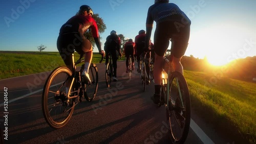 Cyclists riding bicycles in golden sunset lights photo