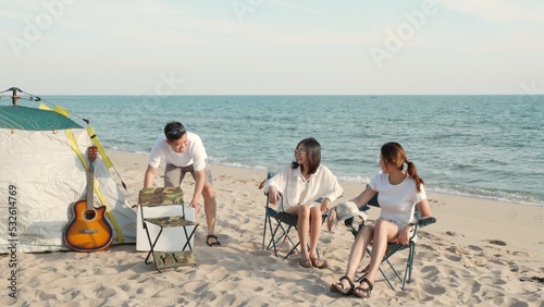 Happy friends with drinks in camp and laughing together in holidays on sand beach near camping tent vacation time at sunset, Young Asian group woman and man in summer travel outdoor