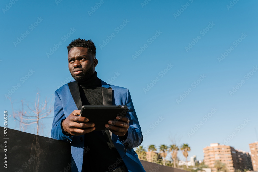 Confident black man browsing tablet on street Confident black man browsing tablet on street