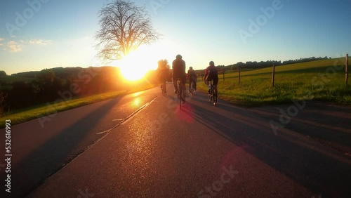 Cyclists cycling on mountain road in sunset lights photo