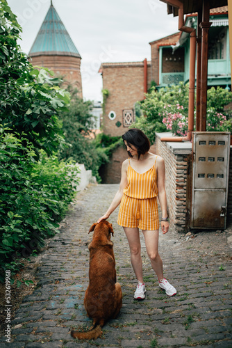 Attractive girl petting a dog on an old eastern pedestrian street photo