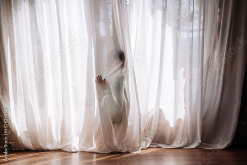 Little girl playing hidden behind curtains