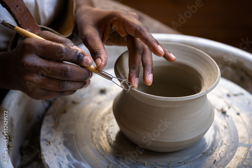 Closeup of woman shaping clay edges on pottery wheel photo