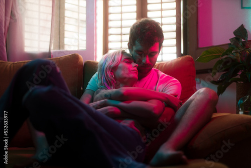 Intimate lovers hug on the sofa with neon lighting 