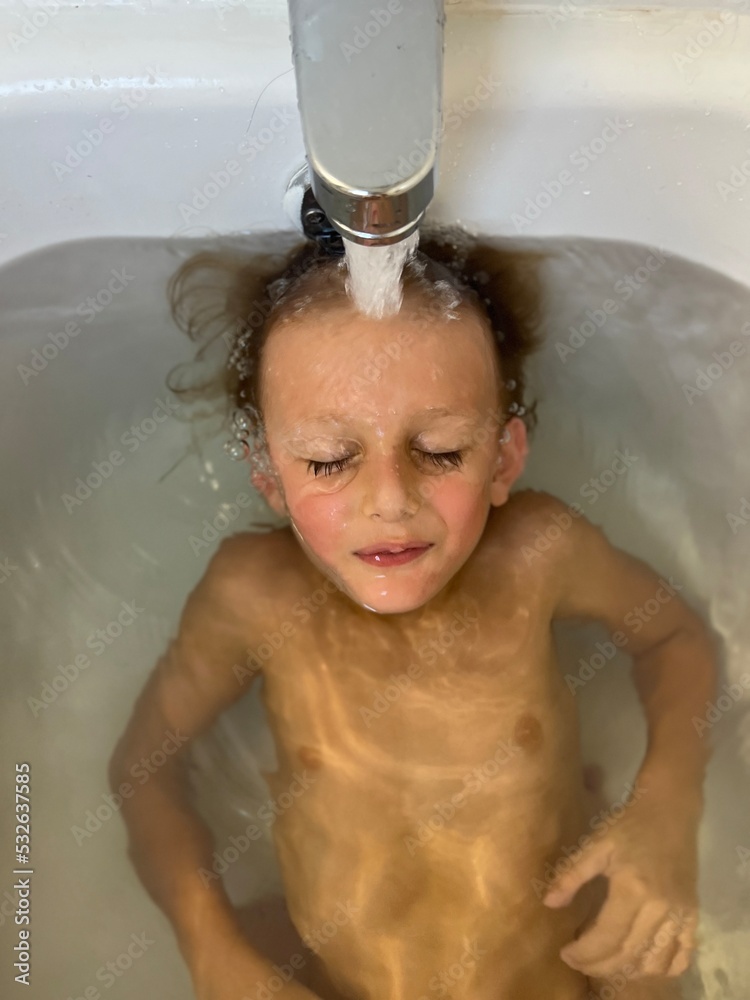 A blonde boy floats under the water as his bath fills A blonde boy floats under the water as his bath fills