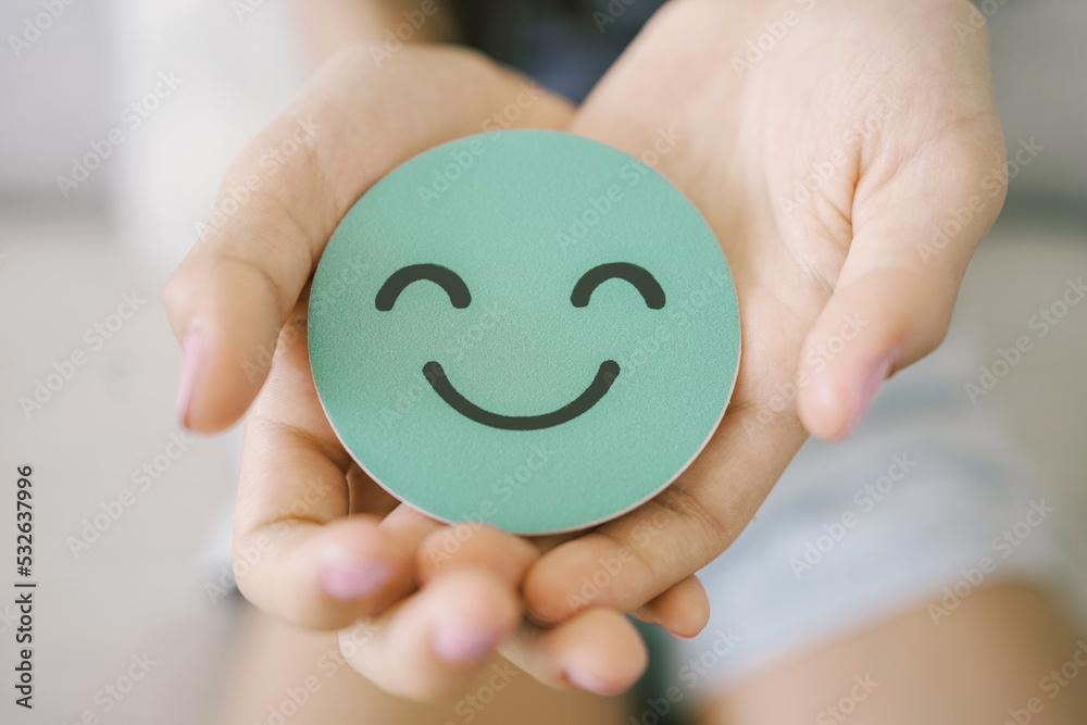 Hands holding green happy smile face paper cut, good feedback rating,think positive, customer review, assessment, child wellness,world mental health day, Compliment Day - obrazy, fototapety, plakaty 