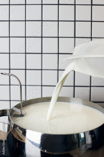 The process of making homemade yogurt. Milk is poured into a container for heating. Vertical photo.