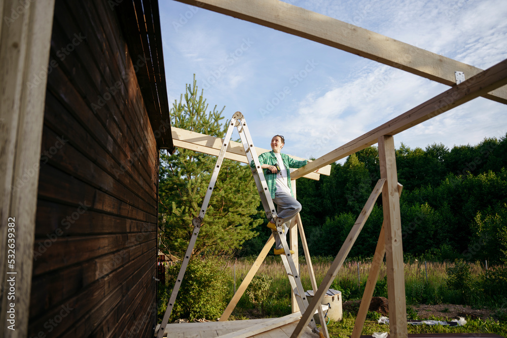 A female carpenter at work on a project in the backyard A female carpenter at work on a project in the backyard