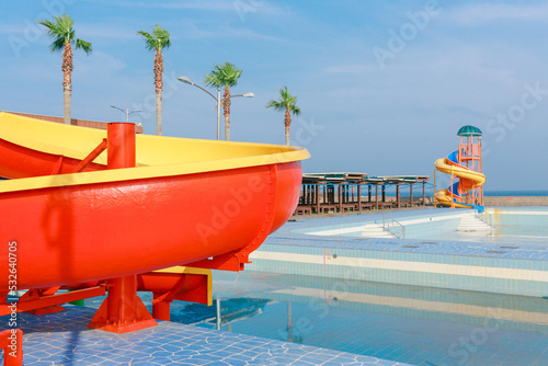 An empty pool and colorful slide by the beach. photo